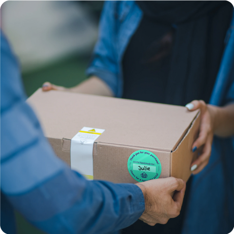 Picture shows a person handing a package with teal custom label.